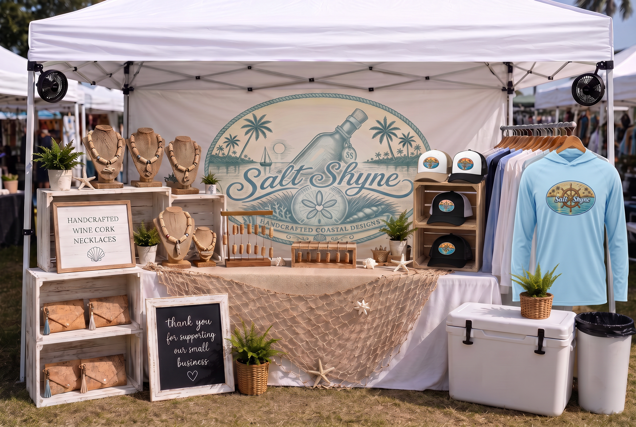 10x10 Salt Shyne Coastal Collection booth mockup with full wine cork necklace displays, a wooden rack of Coastal trucker hats, the light blue Salt Shyne ship wheel hooded sunshirt, and the Coastal Collection badge banner